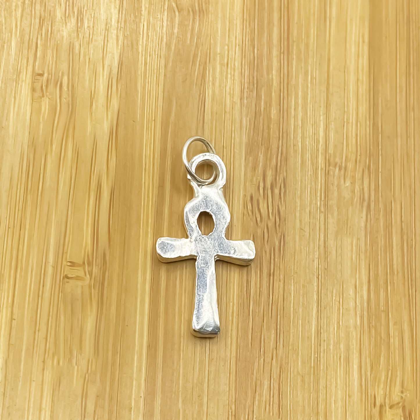 Ankh Pendant close-up showing oxidised silver or gold texture on wood. Egyptian African