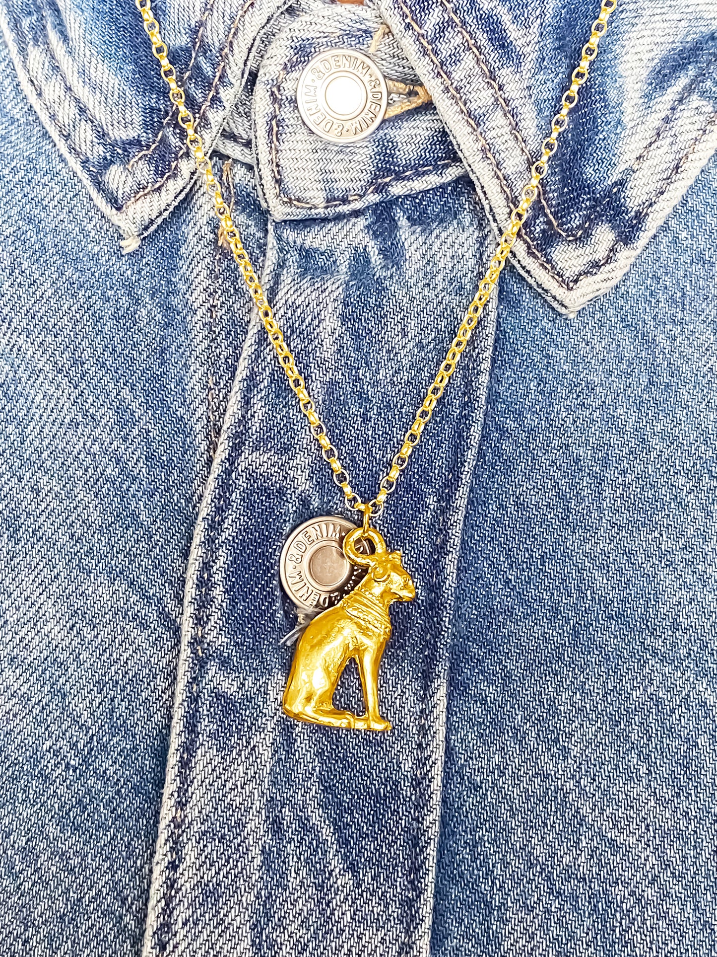 Handmade gold Bast Cat Pendant on denim jacket, featuring Egypt’s adored feline goddess. MOCA Jewellery, free shipping.