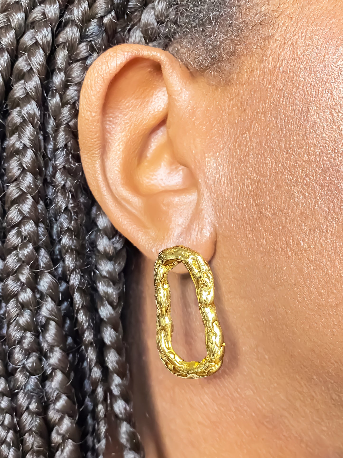 Model wearing gold Flow Loop Earrings by MOCA Jewellery, elegant handmade statement piece with a minimal textured loop design.