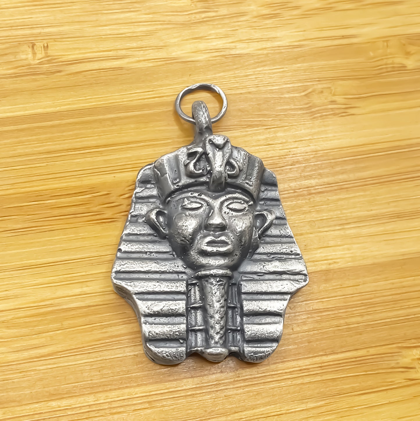 Pharaoh Pendant laid on wood showing texture - oxidised Egyptian African gold or silver free shipping