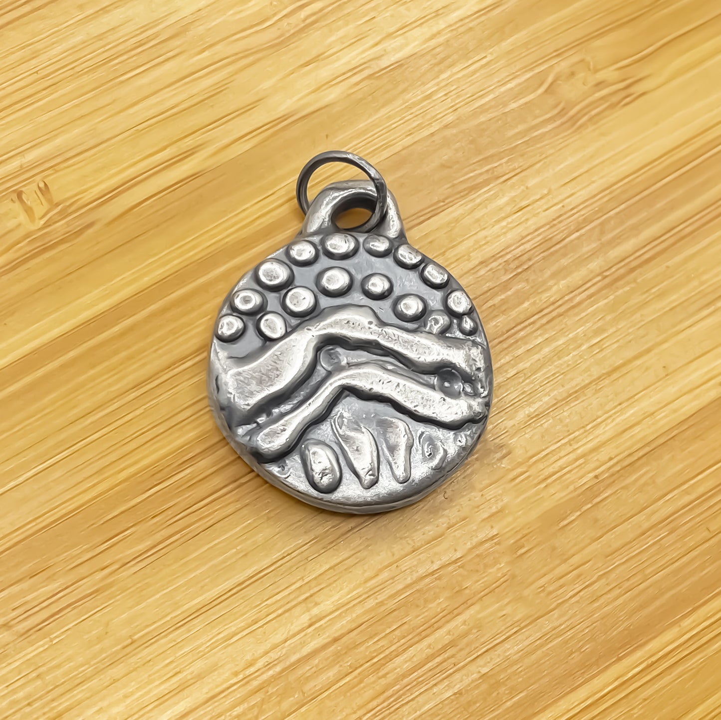 Round Dotty Pendant laid flat on wood for contrast - textured, happy buddha, oxidised organic texture gold or silver free shipping