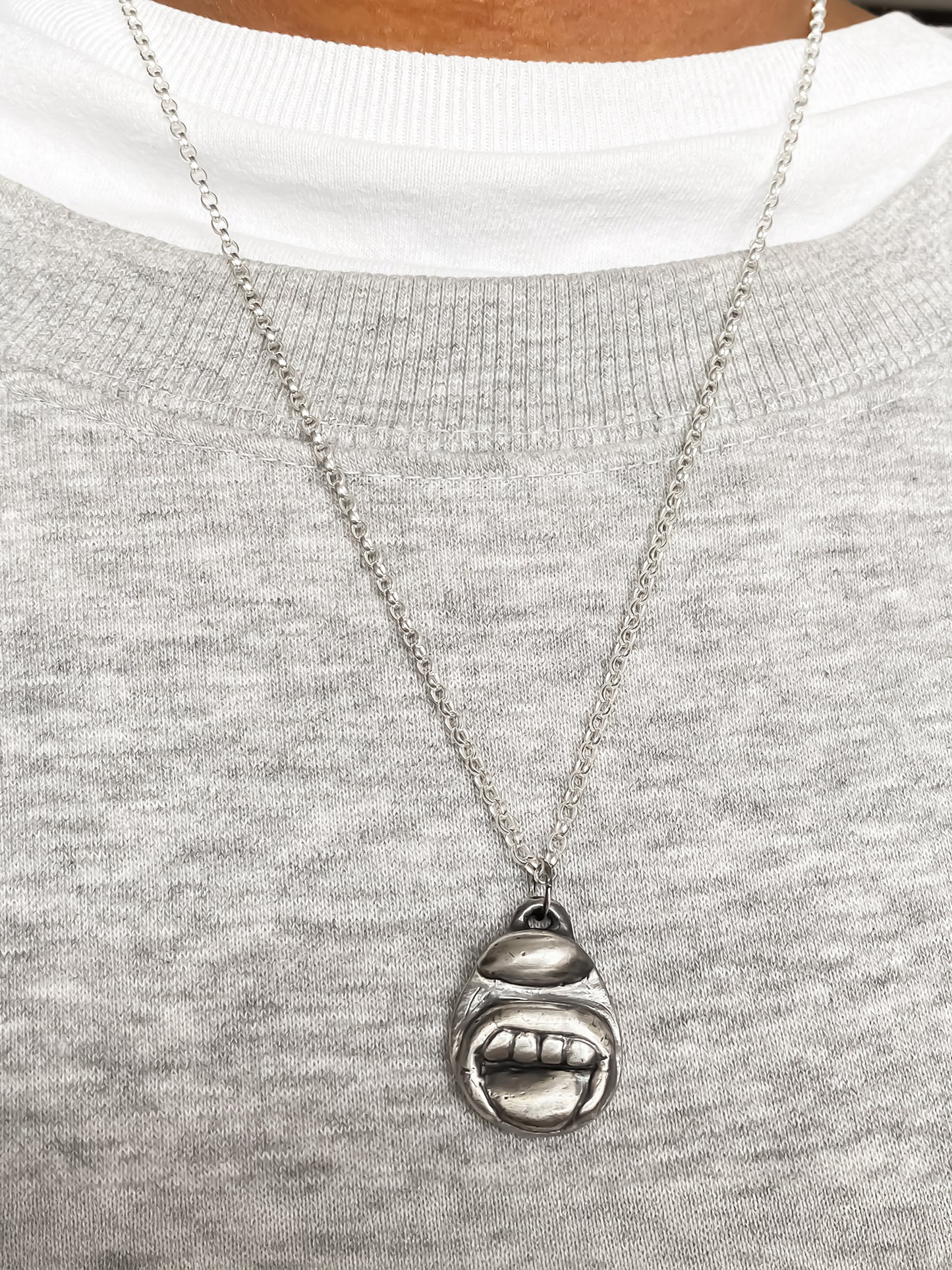 Tongue & Teeth Pendant worn on chest with soft backdrop - tongue smile mouth lips charming oxidised organic texture gold or silver free shipping