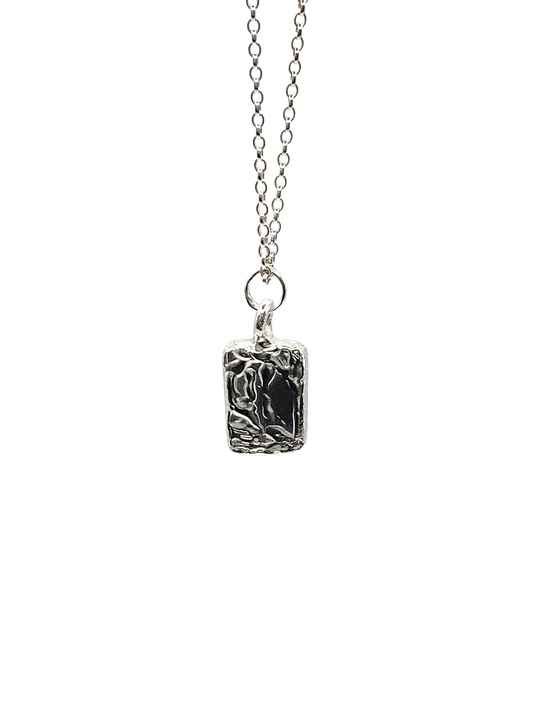 Close-up of rectangular sculpted pendant on chain, textured silver, sleek and minimal design with delicate lines and free shipping