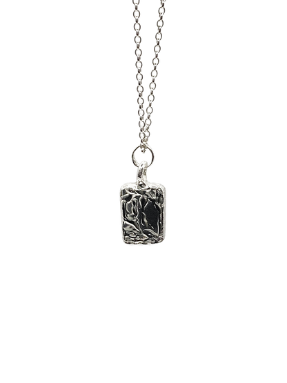 Close-up of rectangular sculpted pendant on chain, textured silver, sleek and minimal design with delicate lines and free shipping