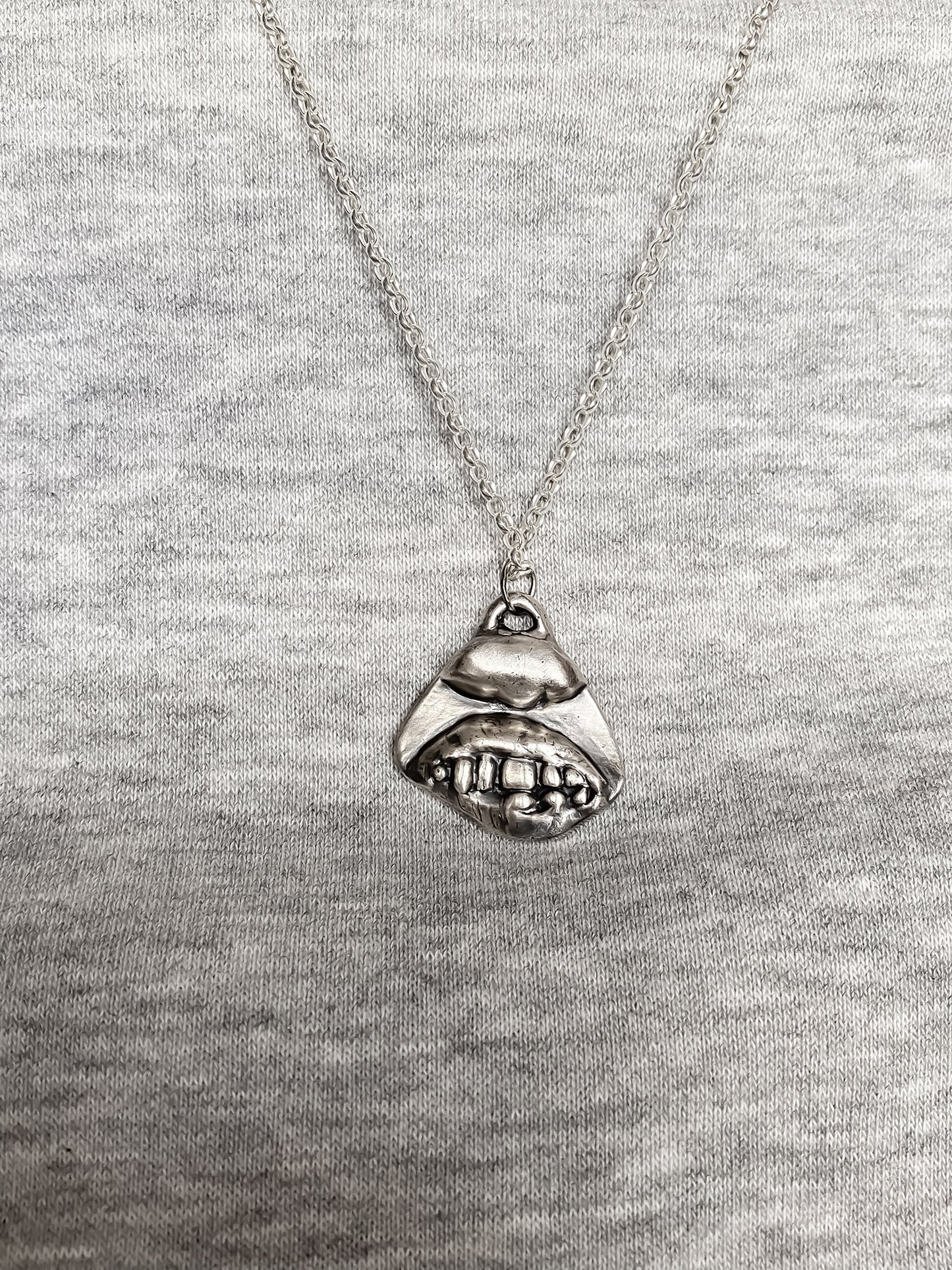 Smiler Pendant worn over grey knit for everyday styling - smile mouth lips teeth charming oxidised organic texture gold or silver free shipping