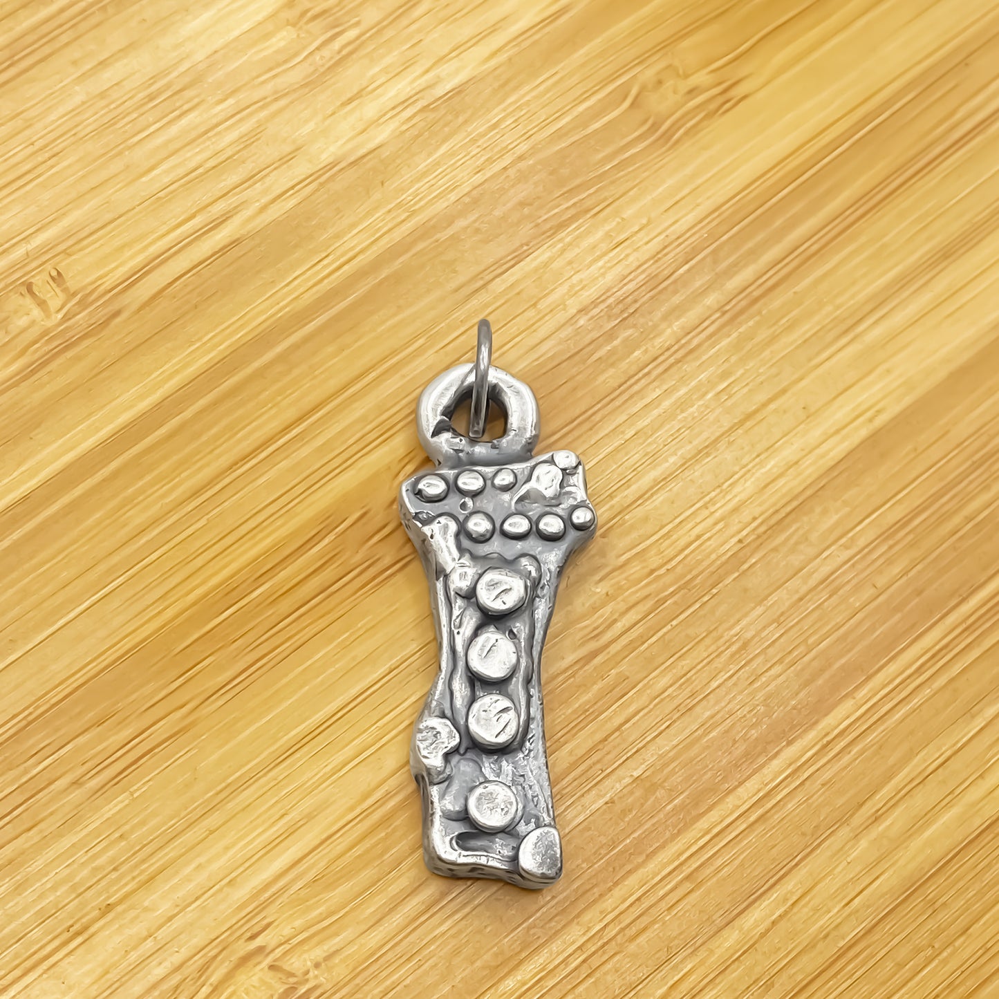 Twig Pendant placed on wood surface to highlight form - charming oxidised organic texture gold or silver free shipping